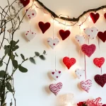 "Heart-shaped hanging decorations with string lights on a branch, creating a romantic wall display."